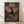 May include: Framed anime poster leaning against white wall on light wooden floor. Poster shows samurai character mid-leap with flowing sword trail over seaside dock at sunset. Features Japanese text at top, English subtitle "The Blade of Fate, At the Seaside Dock" at bottom. Warm orange sky contrasts with detailed traditional Japanese harbor town setting. Two background figures visible on wooden pier. Natural wood frame surrounds artwork.