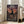 May include: Framed anime poster leaning against white wall in bright living room with beige sofa. Artwork shows samurai character in dark robes wielding sword on wooden dock at sunset, with traditional Japanese buildings and orange sky. Japanese and English text visible. Light wood frame, poster reaches mid-height of sofa arm.
