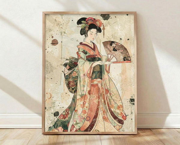 May include: Framed vintage-style Japanese geisha artwork displayed against white wall on wooden floor. The poster shows a geisha in elaborate layered kimono with coral, green, and cream floral patterns, holding a decorative fan. Her black hair is styled in traditional updo with ornamental accessories. The artwork has an aged, weathered appearance with ink splatters and distressed texture on cream background, housed in light wood frame.