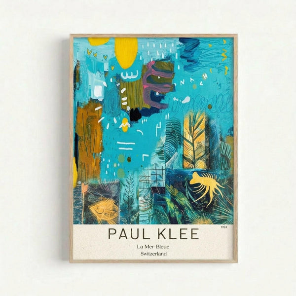 Framed art print featuring Paul Klee's abstract painting with vibrant turquoise background, yellow sun, and layered organic shapes including fish, leaves, and botanical forms. Mixed media artwork combines painterly textures with linear drawings in blues, greens, yellows, and earth tones. White text below reads "PAUL KLEE La Mer Bleue Switzerland" with "1924" in corner. Light wood frame against white wall.