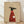 May include: Framed poster print leaning against white wall on wooden floor with natural lighting and shadows. Shows minimalist illustration of black greyhound wearing red ribbed sweater, holding white coffee mug. Tan beige background with "Brewed for Good Dogs" text and steam wisps. Light wood frame, clean modern home decor style.
