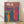 May include: Colorful surreal art print in wooden frame leaning against white wall on light wood floor. Features swirling rainbow lines forming sky and waterfall, with orange striped figure standing in blue wavy water. White Japanese characters at top. Vibrant psychedelic style with flowing organic patterns in pink, blue, green, yellow, and red tones creating dreamlike landscape scene.