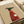 May include: Art print on beige paper showing a black greyhound wearing a red ribbed sweater, holding a white coffee cup with steam rising above. The minimalist illustration has "Brewed for Good Dogs" text at top. Print is displayed on white wrapping paper with cream ribbon nearby, creating a gift presentation scene.