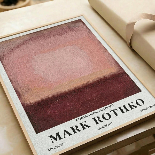 May include: Abstract art print with gradient bands in warm burgundy, coral pink, and cream tones creating a horizon-like composition. The poster sits on cream paper with black text below the artwork, accompanied by beige ribbon on a neutral surface.