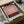 May include: Abstract gradient poster print in warm earth tones ranging from dusty pink at top to deep burgundy at bottom, displayed in black frame with white matting. The artwork features soft horizontal color transitions creating an atmospheric effect. Shown nestled in brown cardboard packaging with white tissue paper on wooden surface.