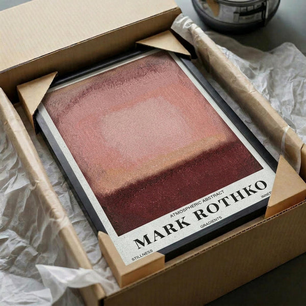 May include: Abstract gradient poster print in warm earth tones ranging from dusty pink at top to deep burgundy at bottom, displayed in black frame with white matting. The artwork features soft horizontal color transitions creating an atmospheric effect. Shown nestled in brown cardboard packaging with white tissue paper on wooden surface.