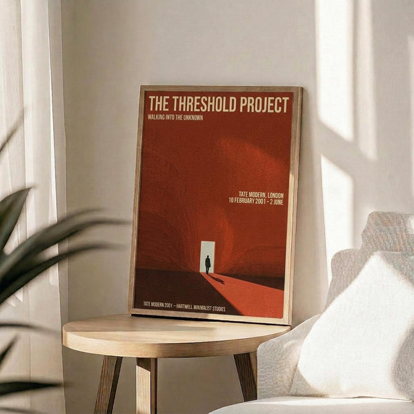 May include: Orange and red minimalist art poster in thin wooden frame, leaning against white wall on round wooden side table next to beige upholstered chair. Natural sunlight creates soft shadows across the scene. Poster features geometric design with small silhouette figure and white text against warm gradient background.
