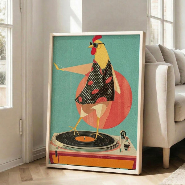 May include: Framed poster print leaning against white wall in bright living room with beige sofa and windows. Artwork shows stylized yellow rooster wearing black polka dot dress with red accents, sunglasses, and red comb, dancing on vinyl record turntable against turquoise background with large coral circle. Retro mid-century modern illustration style with textured appearance in light wood frame.