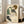 May include: Large framed art print leaning against white wall next to beige sofa in bright living room with hardwood floors and windows. Print features woman with curly brown hair in green top and white skirt with black stockings, rendered in expressive sketch style with muted colors on cream background.