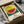 May include: Framed watermelon print in wooden box with tissue paper. Artwork shows sliced watermelon with green rind and pink flesh with black seeds against yellow background with blue and green geometric patterns below. Japanese characters and English text about courage visible at bottom. Print appears textured with dotted, stippled effect throughout.