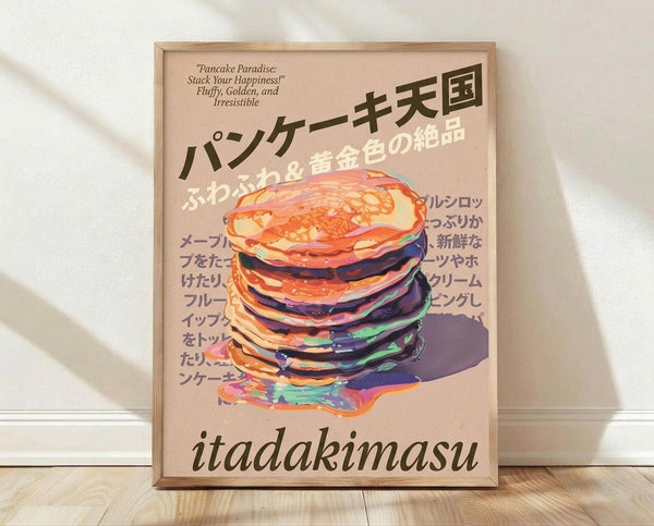 May include: Framed poster print leaning against white wall on light wooden floor with natural shadows. Features colorful illustrated stack of pancakes with vibrant dripping syrup in rainbow hues against peachy pink background. Japanese text at top and "itadakimasu" at bottom. English subtitle reads "Pancake Paradise: Stack Your Happiness! Fluffy, Golden, and Irresistible." Light wooden frame complements the warm tones of the artwork.