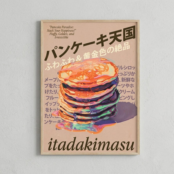 May include: Framed poster on white wall featuring a tall stack of colorful pancakes with syrup dripping down. The artwork has a pink background with Japanese text and "Pancake Paradise: Stack Your Happiness! Fluffy, Golden, and Irresistible" at top, "itadakimasu" at bottom. Light wood frame against textured white wall.