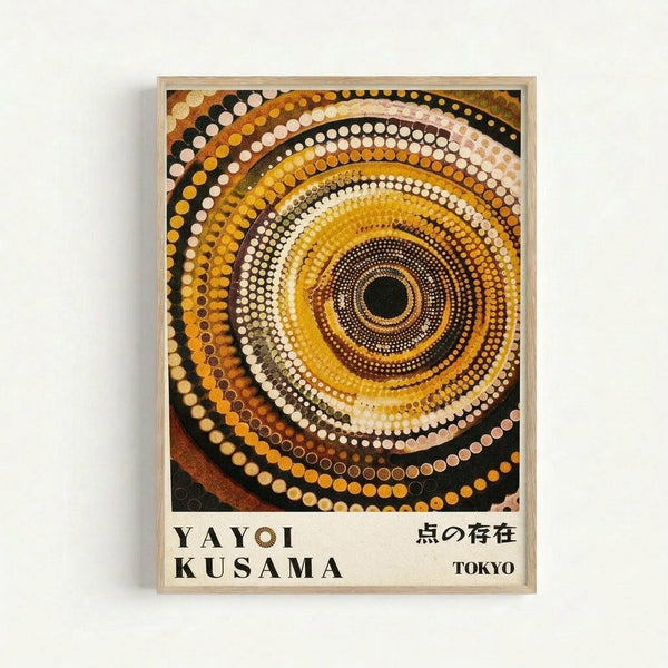 A framed poster featuring concentric circles made of dots in warm earth tones - yellows, oranges, browns, creams, and black. The hypnotic spiral pattern radiates outward from a dark center, creating a mesmerizing optical effect. Text at the bottom reads "YAYOI KUSAMA" and Japanese characters, with "TOKYO" in the corner. The artwork is displayed in a light wooden frame against a white wall.