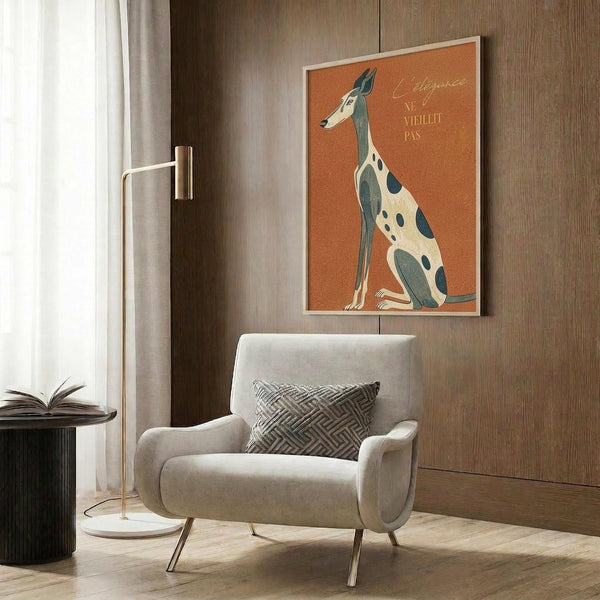 May include: Stylized greyhound poster with orange background and French text displayed in modern living room setting. Cream upholstered armchair with geometric pillow sits beneath framed artwork on wood-paneled wall. Gold floor lamp and dark round side table with open book complete the contemporary interior scene.