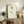 May include: Framed minimalist line art print featuring a single rose with yellow and burgundy petals and simple black stem, displayed on rustic wooden sideboard alongside fern plant, ceramic vase, stacked books, and brown leather chair in warm-toned living room setting