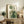 May include: Framed botanical abstract art print with green geometric shapes, circles, arches, and plant stems displayed on rustic wooden sideboard alongside fern plant, books, and ceramic vase in neutral-toned living room setting