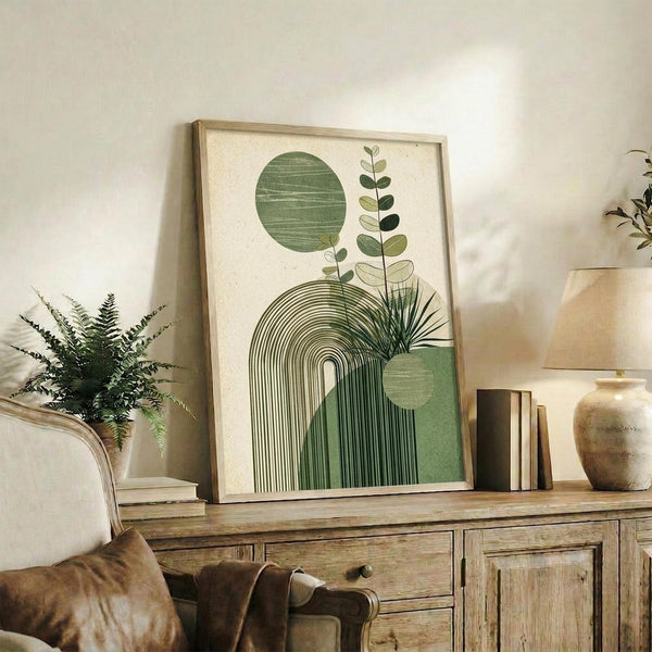 May include: Framed botanical abstract art print with green geometric shapes, circles, arches, and plant stems displayed on rustic wooden sideboard alongside fern plant, books, and ceramic vase in neutral-toned living room setting