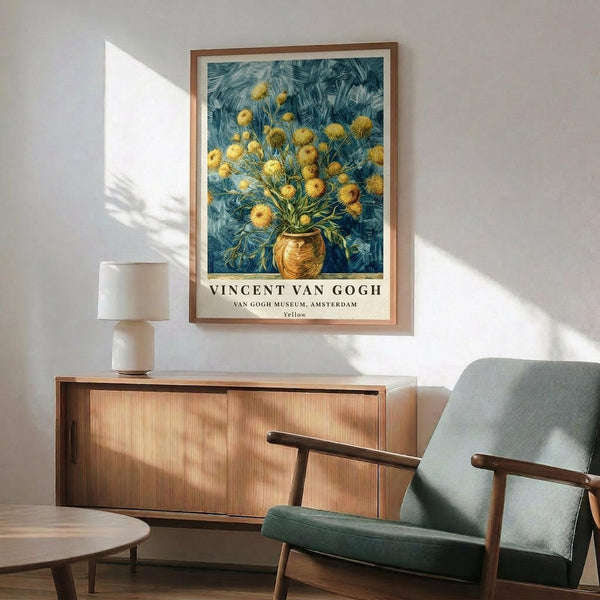 May include: Van Gogh yellow flower artwork in wooden frame hanging on white wall above wooden sideboard with white lamp. Green upholstered armchair with wooden arms sits nearby alongside round wooden coffee table. Sunlight creates geometric shadows across the minimalist room setting.