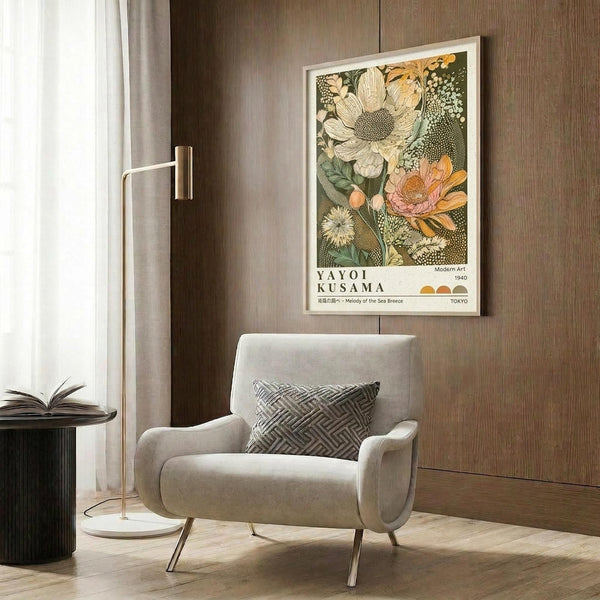 May include: Framed botanical art print featuring large flowers in cream, orange, and pink tones with detailed leaves on dark green background, displayed above beige upholstered chair with geometric pillow in modern living room with wood paneled walls and brass floor lamp