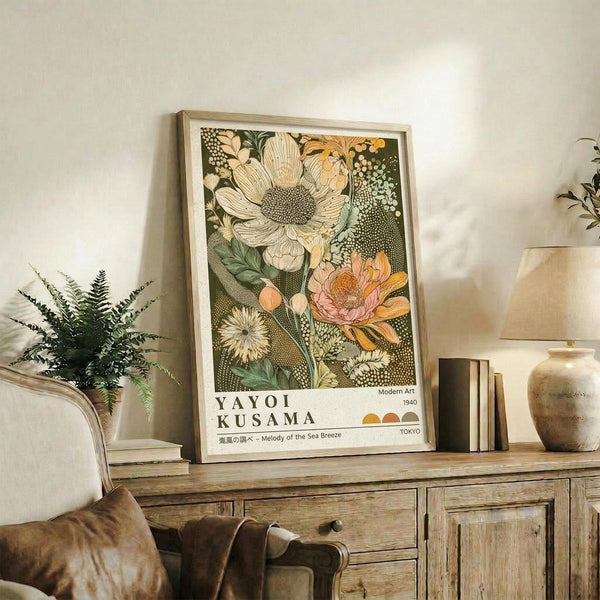 May include: Framed botanical art print featuring large detailed flowers in cream, orange and green tones with dotted patterns, displayed on rustic wooden sideboard next to fern plant, ceramic vases, and stacked books in neutral-toned living room setting