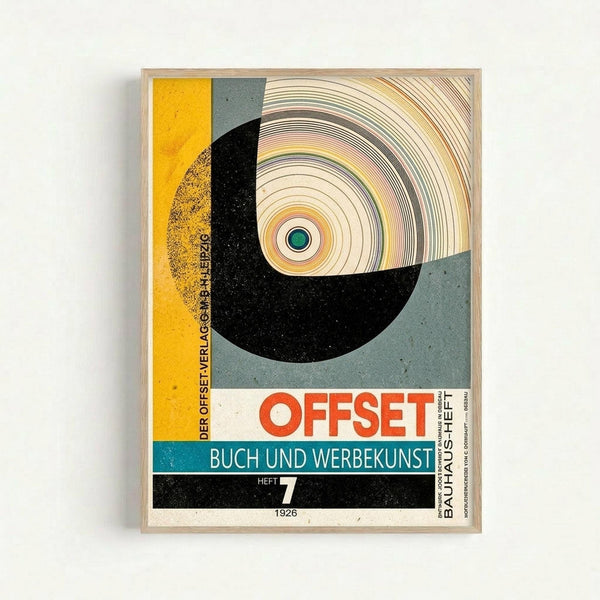 Vintage 1926 Bauhaus poster featuring bold geometric design with circular motif in yellow, gray, black and teal color blocks. Central spiral pattern with green dot surrounded by concentric circles. German text "OFFSET BUCH UND WERBEKUNST HEFT 7 1926" in red and white lettering. Framed in light wood frame against white wall, showing modernist typography and abstract geometric composition typical of Bauhaus design movement.
