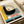 May include: Vintage 1926 Bauhaus poster print displayed flat on white surface next to rolled cream paper tube. Design features bold geometric composition with large black semicircle containing concentric rings in cream, yellow, and orange tones with green center dot. German text "OFFSET" in red letters and "BUCH UND WERBEKUNST" in white on teal band. Yellow section on left with black German text. Speckled texture throughout design gives aged appearance.