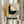 May include: Person holding framed vintage Bauhaus poster in light wood frame against neutral curtained background, with dried pampas grass visible to left. Artwork features bold geometric design with yellow, gray, black and teal color blocks, concentric circles, and German text reading "OFFSET BUCH UND WERBEKUNST" dated 1926. Mid-century modern aesthetic with textured, weathered appearance.