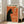 May include: Framed vintage-style poster featuring a black cat silhouette smoking a cigarette with green smoke curls against an orange background. French text reads "LE CHAT NOCTURNE" at top. The wooden-framed artwork leans against a white wall next to a beige upholstered chair in a bright, minimalist room with large windows and natural lighting.