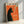 May include: Framed vintage-style poster featuring a black cat silhouette with pointed ears smoking a cigarette against a vibrant orange background. Green smoke curls upward from the cigarette. The cat has a yellow-green eye and visible whiskers. French text reads "LE CHAT NOCTURNE" at top with exhibition details below. The poster is displayed in a light wood frame leaning against a white textured wall with natural lighting creating diagonal shadows.