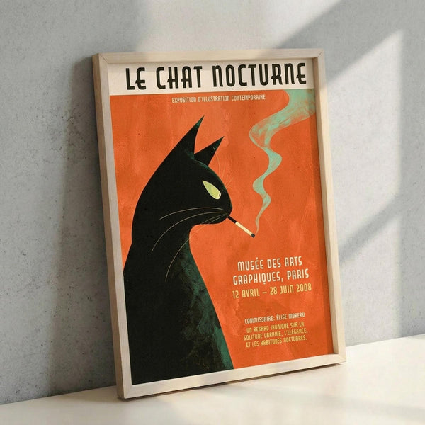 May include: Framed vintage-style poster featuring a black cat silhouette with pointed ears smoking a cigarette against a vibrant orange background. Green smoke curls upward from the cigarette. The cat has a yellow-green eye and visible whiskers. French text reads "LE CHAT NOCTURNE" at top with exhibition details below. The poster is displayed in a light wood frame leaning against a white textured wall with natural lighting creating diagonal shadows.