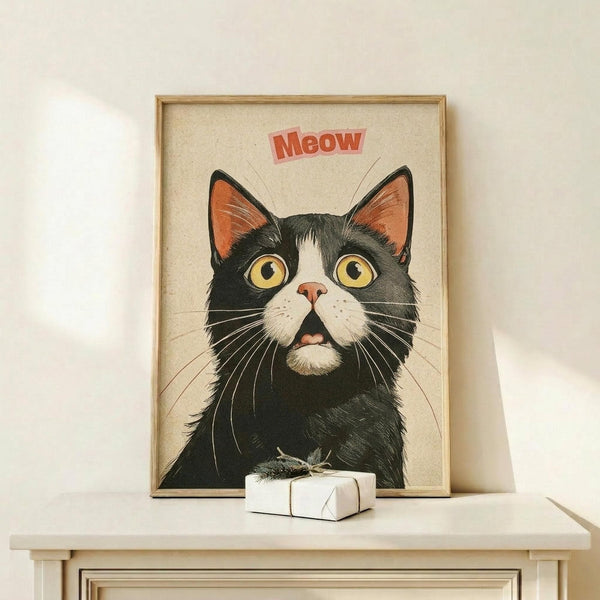 May include: A framed poster featuring a black and white tuxedo cat with large golden eyes and pink inner ears against a cream background, with red "Meow" text above. The artwork shows detailed whiskers and fur texture in a vintage illustration style. The wooden frame sits on a light wood shelf next to a small white wrapped gift box against a white wall.