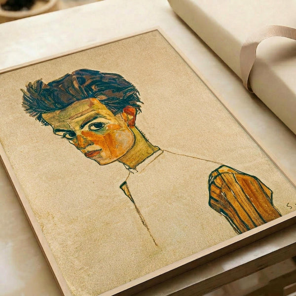 May include: Framed art print of an expressionist self-portrait featuring a man with teal-blue wavy hair and orange-yellow facial tones, wearing a brown striped jacket. The artwork uses bold, sketchy lines on cream-colored paper with visible texture. The print is displayed in a white matted frame on a light wooden surface next to white rolled papers.