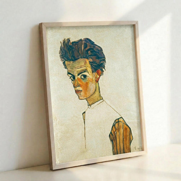 May include: Framed art print leaning against white wall showing expressionist self-portrait of young man with tousled dark hair and intense gaze. Figure wears white shirt with orange and green striped sleeve detail. Artwork features bold outlines, warm earth tones of yellow and orange flesh, set against cream background. Natural wood frame casts soft shadows on textured wall surface.