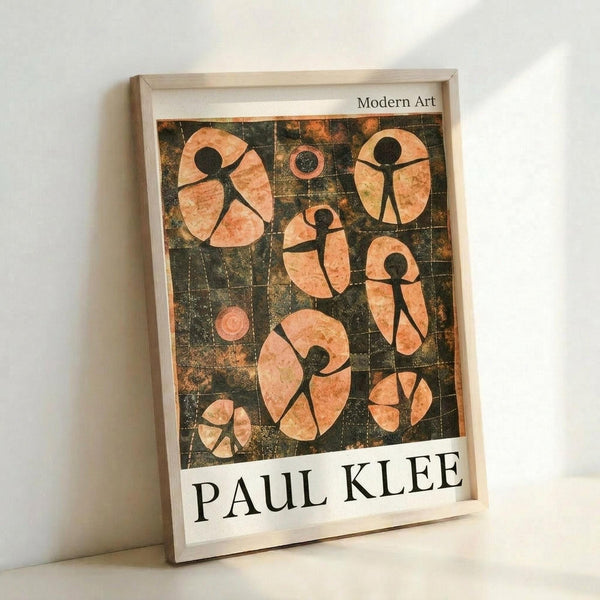 May include: Framed modern art poster featuring abstract stick figures in warm orange and peach tones against a dark gridded background. The minimalist geometric figures appear to be dancing or in motion across oval and circular shapes. White matting surrounds the artwork with "PAUL KLEE" printed at bottom and "Modern Art" at top. Light wood frame leans against white wall casting soft shadows.