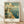 May include: Framed vintage-style poster featuring Navy Pier in Chicago with a large Ferris wheel, ornate buildings with green domes, sailing boats on blue water, and "Welcome to Illinois" text in warm earth tones. The wooden-framed print sits on light wood flooring against white walls with soft natural lighting creating gentle shadows.