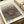 May include: Framed art print featuring a radiating pattern of black dots creating an optical illusion with an orange-brown circle at the center, displayed on a cream colored surface next to rolled white paper. The vintage-style poster shows "YAYOI KUSAMA" at the top, "Modern Art" at the bottom, and "1975" in the corner, with dots arranged in concentric circles that appear to pulse outward from the central orange focal point.