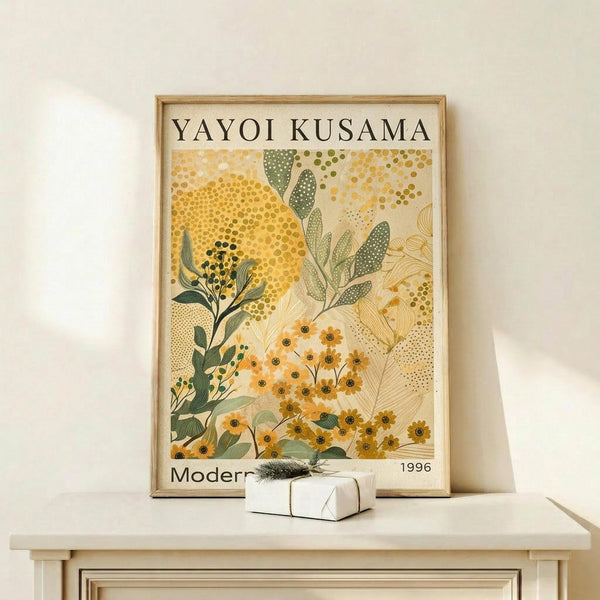 May include: Framed botanical poster with yellow and green floral design featuring dotted patterns and abstract plant motifs in Kusama's distinctive style, displayed on light wood shelf against cream wall with small wrapped gift box beside frame