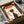 May include: Framed poster with vintage Japanese design featuring silhouette of person in profile against cream background with orange and red geometric elements and Japanese text. Black frame nestled in cardboard shipping box with white tissue paper padding, wooden packing materials visible alongside.