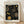 May include: Framed poster print featuring black background with golden circular patterns and dots in various sizes, creating an abstract cosmic design. The artwork shows concentric circles and dotted spirals in gold tones against dark space. Text reads "YAYOI KUSAMA" at top and "Modern Art 1954" at bottom. Light wooden frame sits against white wall on wooden floor with soft natural lighting.