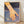 May include: Framed poster print leaning against white wall on wooden floor. Artwork shows a hand reaching into blue water creating concentric ripples, rendered in warm orange and cool blue tones with the word "still" in white text. Natural wood frame, soft window light casting shadows across the scene.