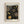 Framed poster with black background featuring golden circular dot patterns in various sizes, resembling celestial or organic forms. White text reads "YAYOI KUSAMA" at top and "Modern Art 1954" at bottom. Light wood frame mounted on white wall in minimalist setting.