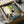 May include: Framed art print in cardboard shipping box with protective wrapping. Illustration shows black cat sitting in yellow chair at blue checkered table with breakfast items - plates of eggs and cookies, coffee cup, orange juice. Yellow "CHOW!" text at top. Cozy kitchen scene with floral wallpaper background in warm, vintage-inspired art style.