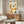 May include: Colorful illustrated poster with twelve diverse portrait illustrations arranged in a grid, featuring people of various ethnicities wearing different clothing and accessories, displayed above a wooden credenza in a modern living room with white curved chair and glass coffee table