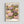 May include: Framed art print displaying colorful water lilies in pink, purple, yellow and white floating on green lily pads with dotted textures against dark water. The botanical artwork features "YAYOI KUSAMA" at top and "Modern Art 1984" at bottom in black text on cream background. Light wood frame hangs on white wall.