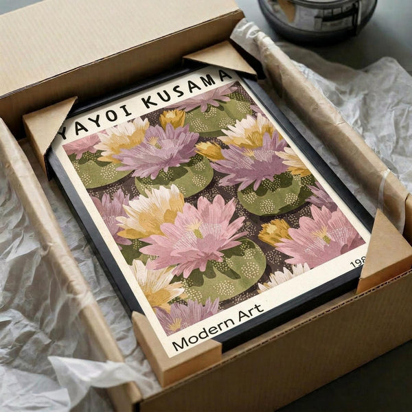 May include: Framed floral art print with pink and yellow lotus flowers on green lily pads against dark background, displayed in black frame inside cardboard shipping box with protective tissue paper and wooden dowel rods