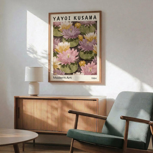 May include: Framed art print featuring colorful water lilies and lily pads in pink, purple, yellow and green tones, displayed above a wooden sideboard in a modern living room with mint green upholstered chair, white table lamp, and natural sunlight casting shadows on white walls.