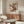 May include: Framed poster featuring colorful water lilies in pink, purple, yellow and white floating on dark water with lily pads, displayed above a mid-century modern walnut credenza in a minimalist living room with white egg chair, glass coffee table, and brass floor lamp