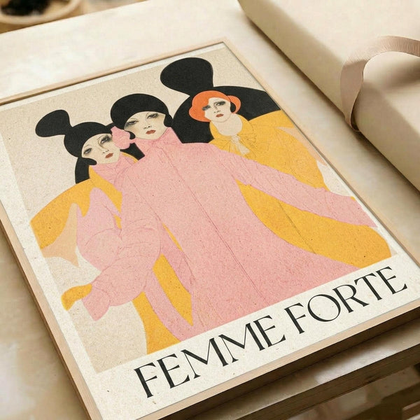 May include: Vintage-style poster print featuring three women with black hair in flowing pink and yellow robes against a cream background, with "FEMME FORTE" text below. The print is displayed in a light wooden frame on a white surface next to rolled paper tubes, showing warm peachy lighting and textured paper appearance.