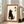 May include: Framed poster print leaning against white wall in bright living room with beige sofa. Artwork shows minimalist black cat silhouette sitting upright looking up, with Japanese kanji characters, on cream background with rust orange border and white frame.