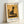May include: Framed poster print leaning against white wall showing Paul Klee's modernist artwork of a stylized black cat silhouette sitting on geometric shapes against warm golden yellow background. Light wood frame with white matting displays the vintage-style art print with "PAUL KLEE" text at bottom and "Modern Art" at top.